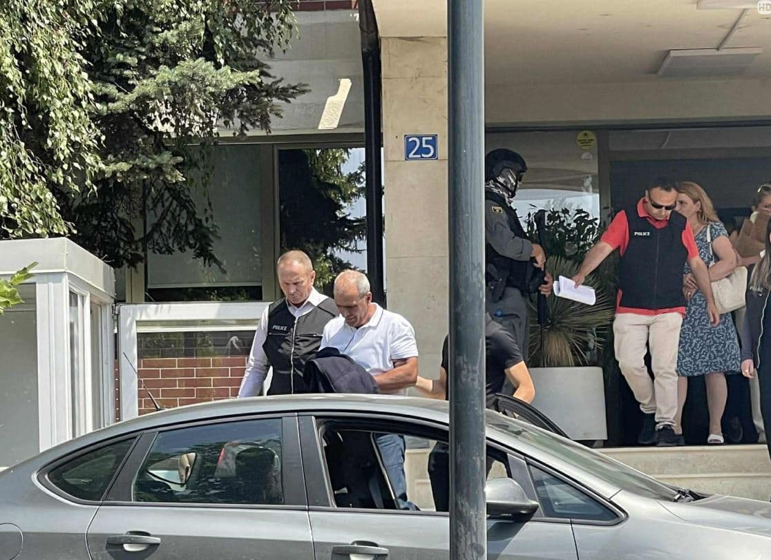 Pamje- Momenti kur zyrtarët e agjencive shtetërore dalin të prangosur, përkujdesen t’i mbulojnë duart