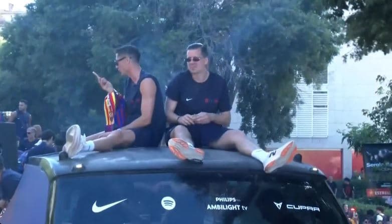 Szczesny dhe Lewa me paketë cigaresh në dorë, mbi autobusin e triumfit në rrugët e Barcelonës